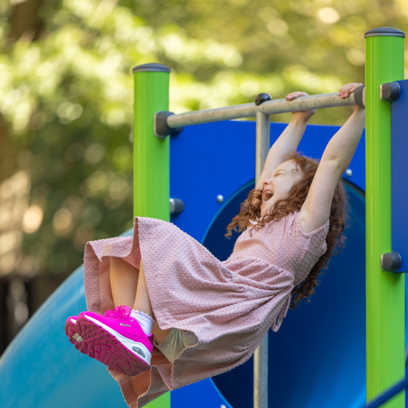 Vertical Girl swinging above slide