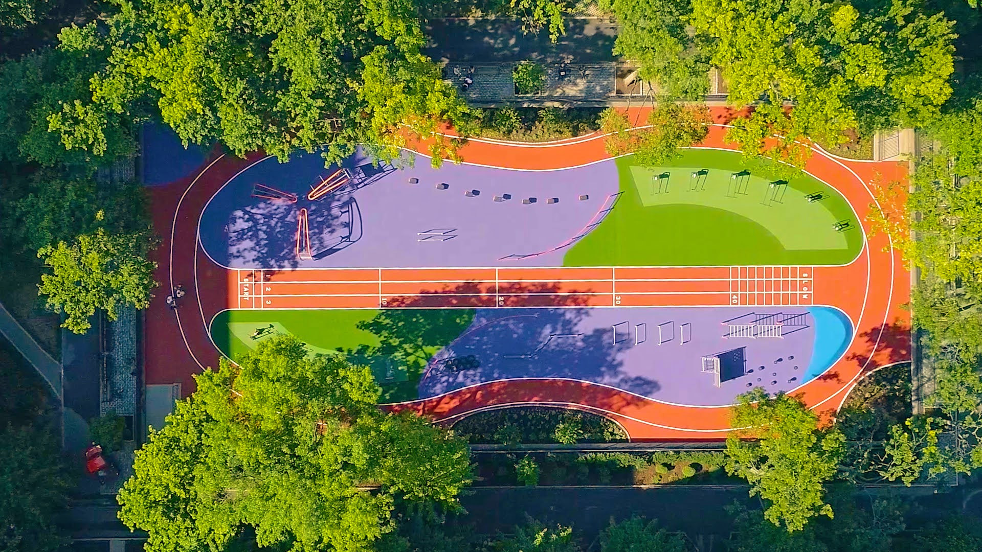 Aerial view of StuyTown outdoor fitness track with sprint lane, agility course, and jogging loop surrounded by trees